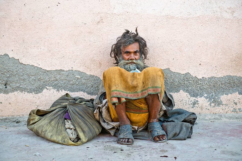 Beggar leaning against a house wall