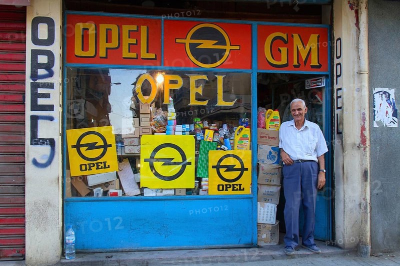 Old man is standing at a shop entrance