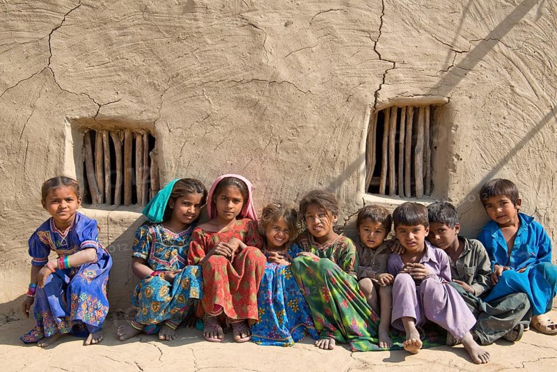 Children sitting in front of a mudbrick house
