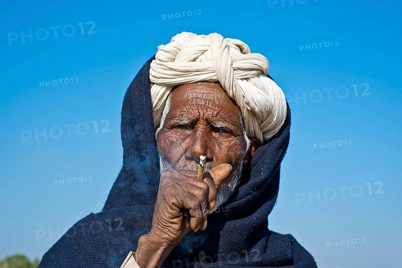 Indian man with a white turban smoking a bidi cigarette