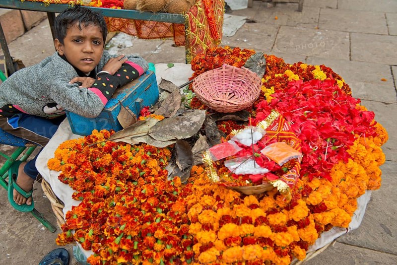 Young boy sitting at a stand for flowers and ritual offerings