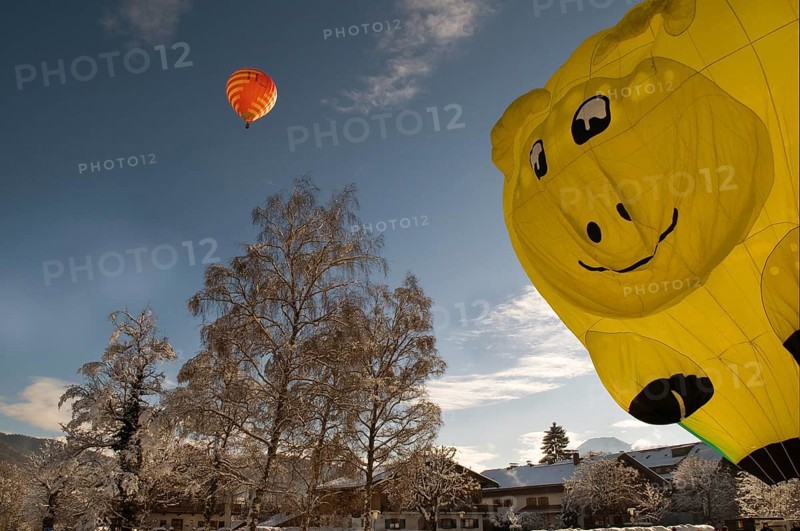 Red hot air balloon travelling against a blue sky