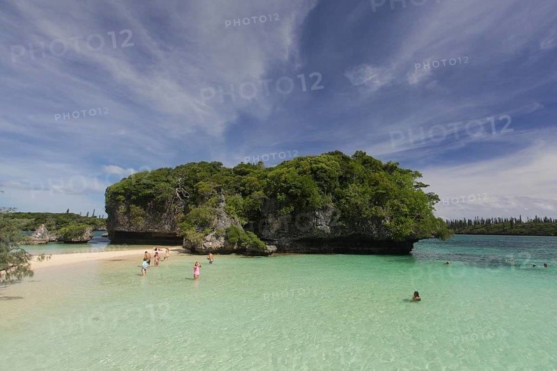 Tourists bathing in front of the sacred rock on the Ile des Pins