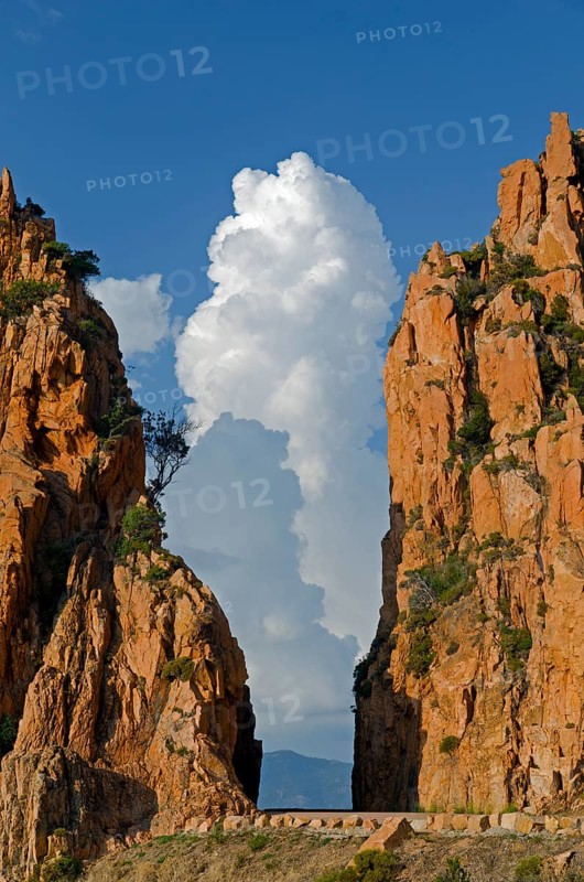 The typical bizarre red rocks of the Calanche of Piana below a blue sky and some clouds. The Calanche of Piana is in the western part of the island Corsica