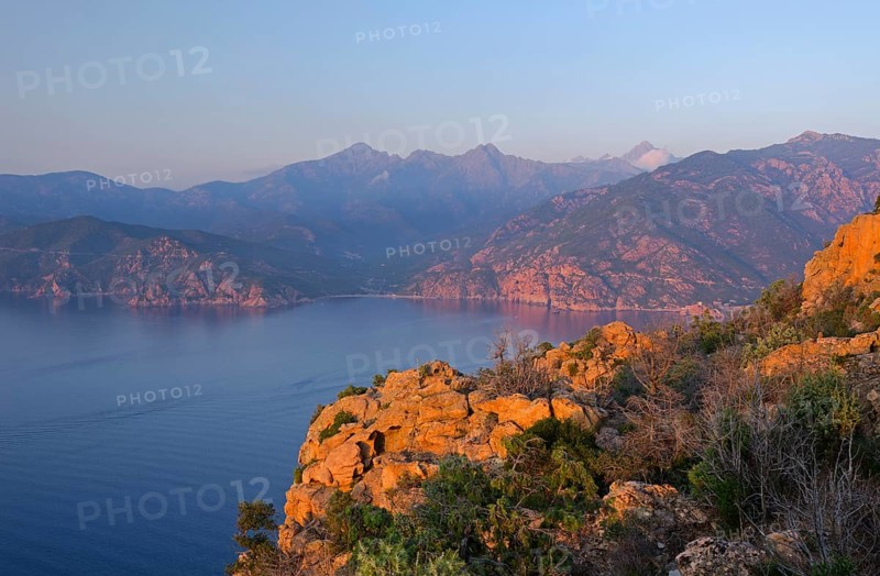 The typical bizarre red rocks of the Calanche of Piana and the mediterranean sea at the Gulf of Porto in the background. The Calanche of Piana is in the western part of the island Corsica