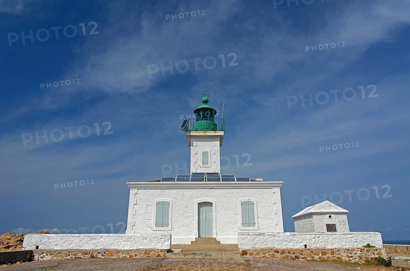 The white lighthouse on the island Ile de la Pietra near L'Île-Rousse below a blue sky with some clouds. L'Île-Rousse  is in the department Haute-Corse