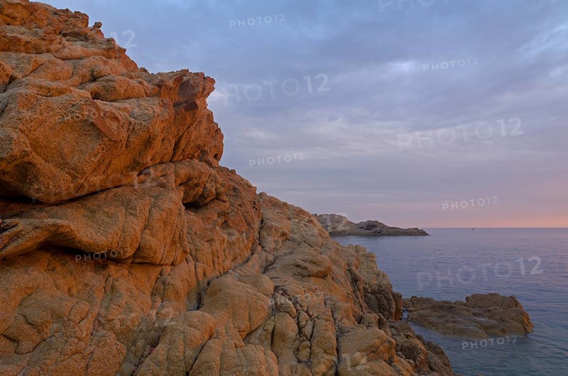 The red granite rocks of the island Ile de la Pietra near L'Île-Rousse illuminated by the first light of the day. L'Île-Rousse  is in the department Haute-Corse