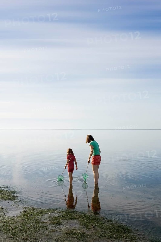 Woman and girl with dip nets standing in the Wadden Sea