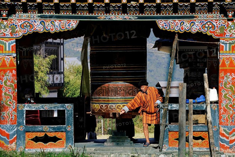 Man turning the large prayer wheel in the town centre of Mongar