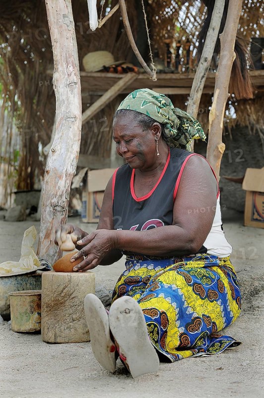 Elderly woman making pottery in front of her stall