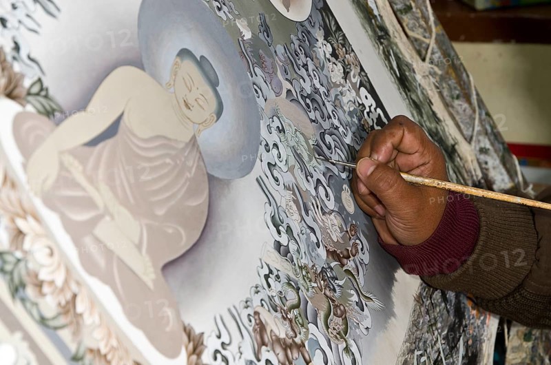 Artist painting a big Thangka in an art school