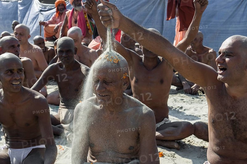 Man putting sand on the head of a another man joining the initiation of new sadhus