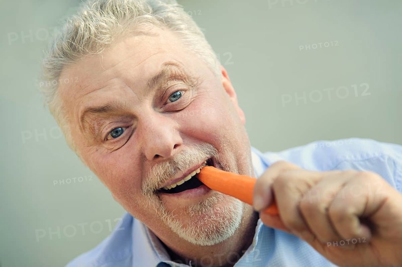 Senior eating a carrot with pleasure