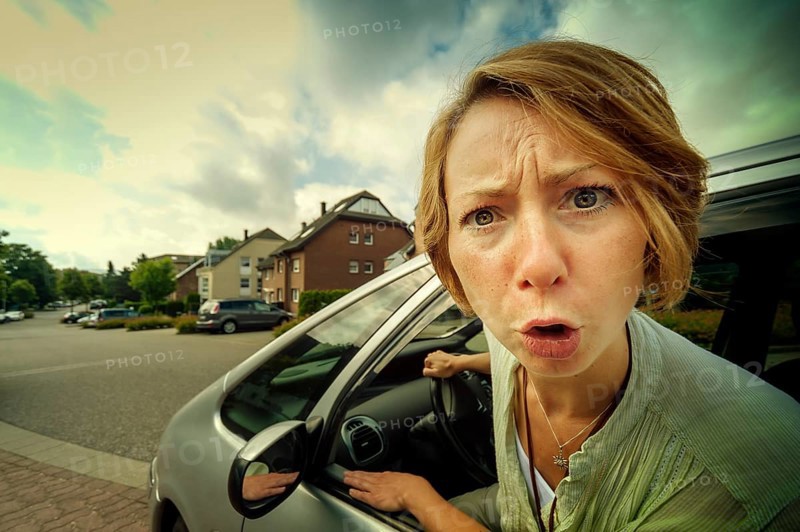 Angry woman car driver sticking out her head out of the window