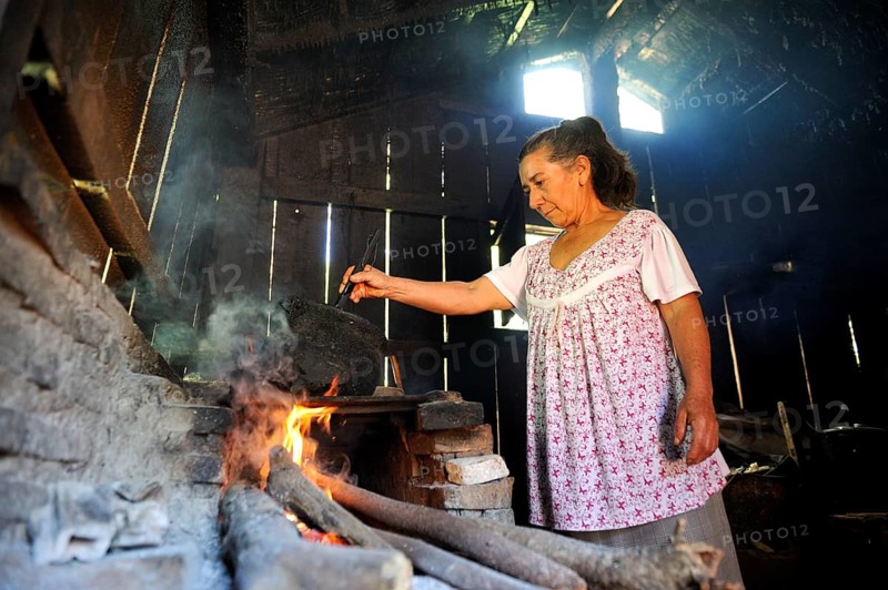 Elderly woman in a basic kitchen cooking on an open fire