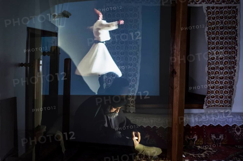 Statue of Mevlana under an holographic projection of a whirling dervish