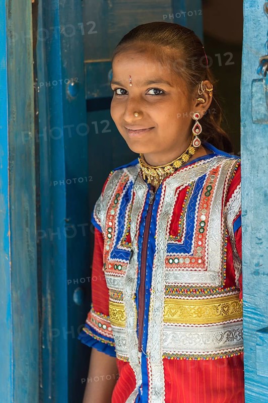 Young girl in traditional colorful clothes standing in a door