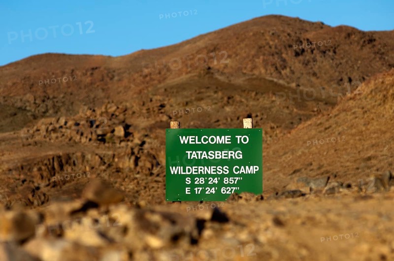Welcome sign visible between rocks with GPS location information at the entrance of the Tatasberg Wilderness Camp