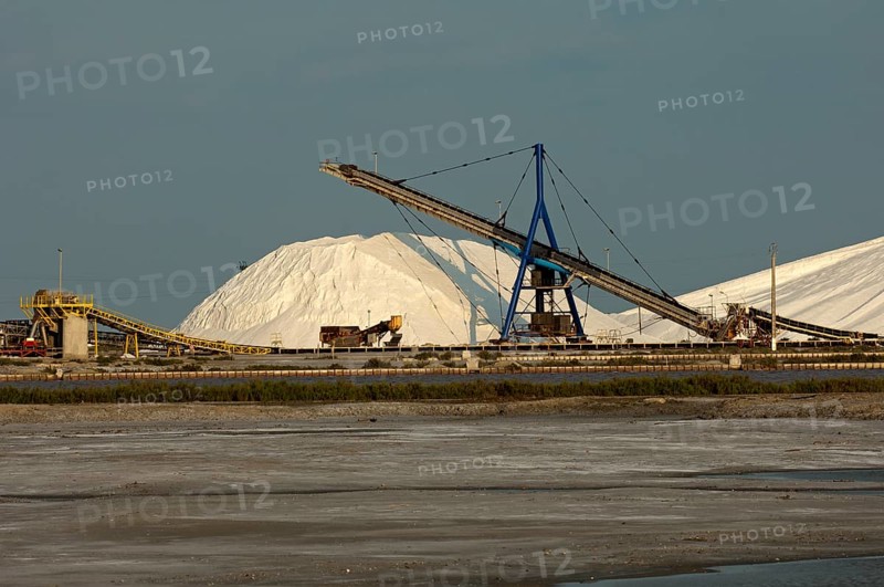 Heap of sea salt at the salt works Salins du Midi with an evaporation basin at front