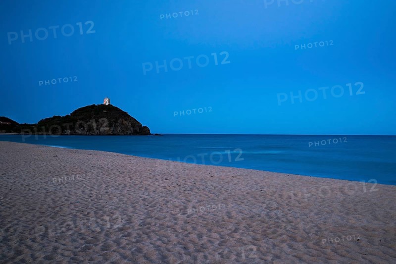 Baia di Chia beach with the Saracen Tower at dusk