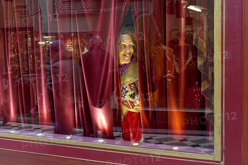 Wax figure looking through a gap in the curtain