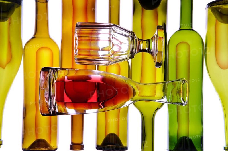 Carafe and wine glass in front of wine bottles