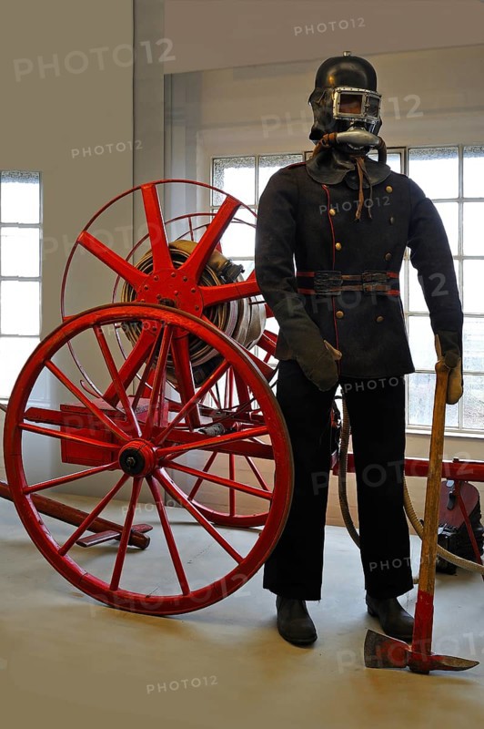 Firefighter wearing a breathing protection mask in front of a hose reel