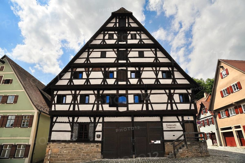 Two-storey half-timbered building on a stone plinth with a steep hipped roof