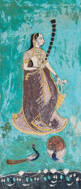 Woman wearing a gilded sari behind peacocks and a lotus pond