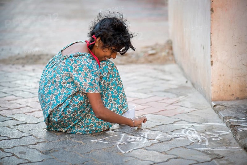Girl creating a traditional Rangoli