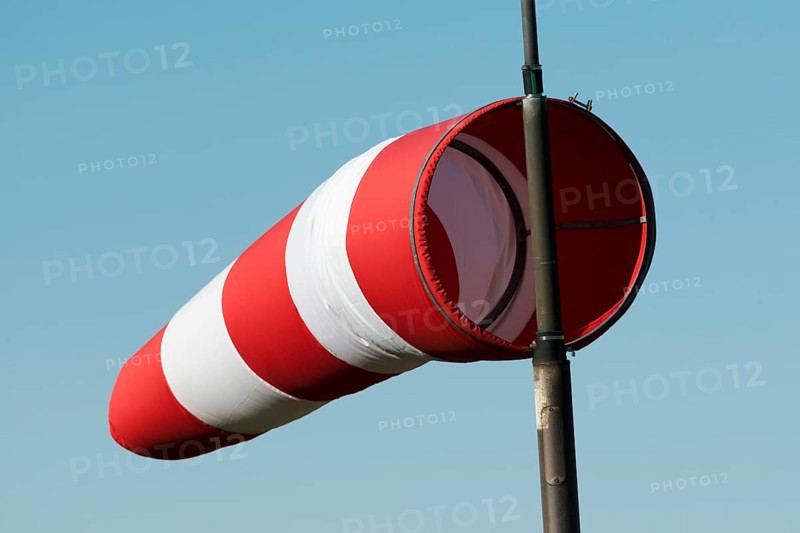 Red and white windsock against a blue sky