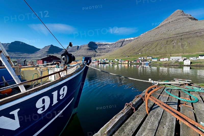 Fishing boat and rusty anchors in the harbour of Hvannasund