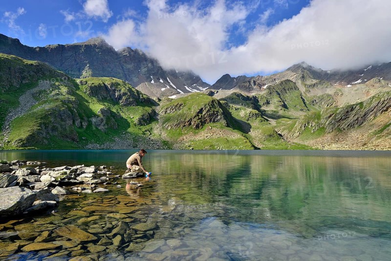 Mountaineer filling a water bottle at Grosser Schwarzsee Lake or Lago Nero