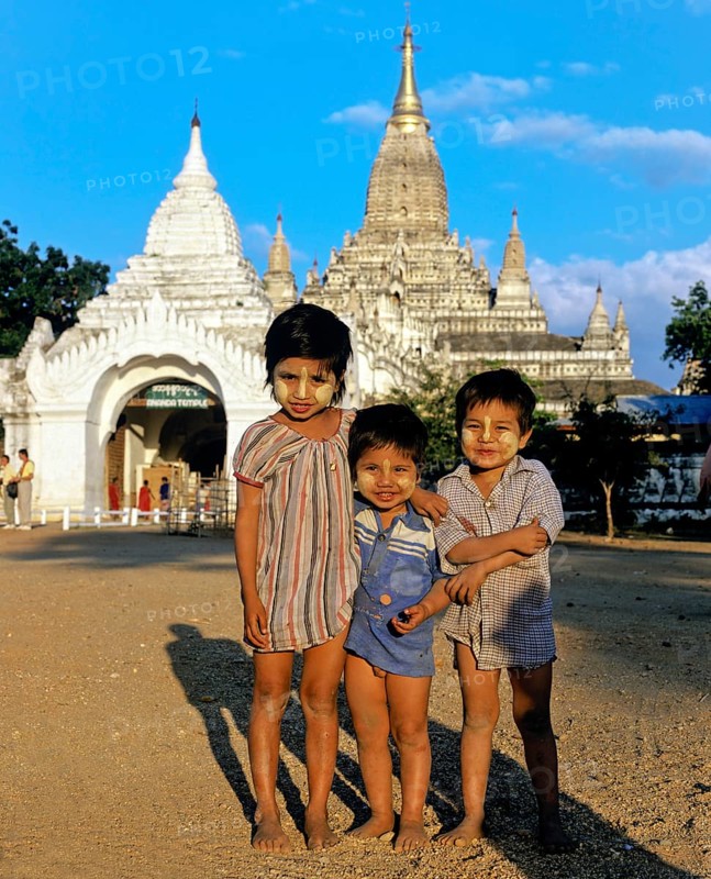 Children with Thanaka paste on their faces in front of Buddhist pagodas