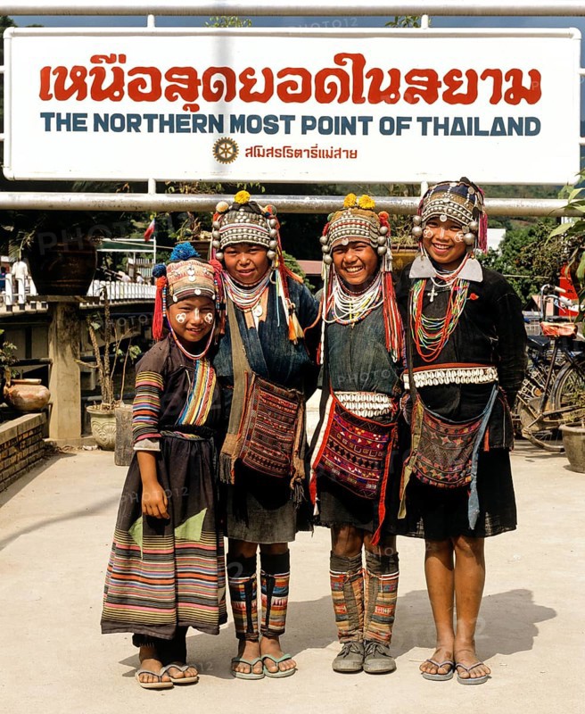 Akha hill tribe girls wearing traditional costumes and headdresses standing at the northernmost point of Thailand