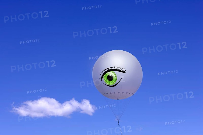 Tethered balloon with the illustration of a human eye against a blue sky with a cloud