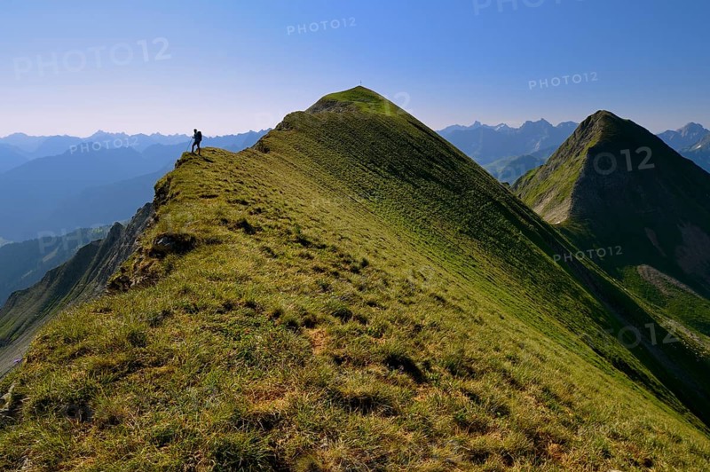 Mountaineer on the grassy summit ridge of Großer Krottenkopf Mountain