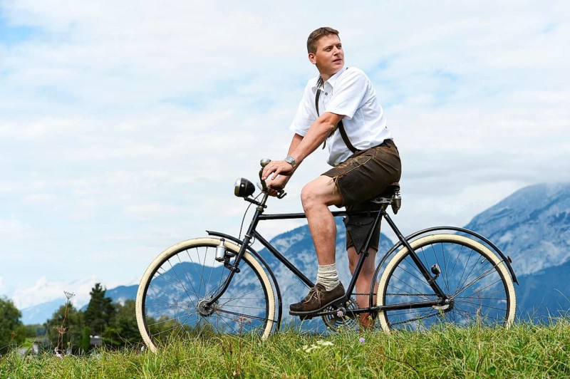 Man wearing leather pants on an old bicycle