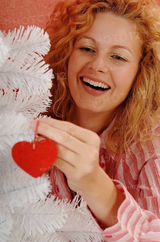 Woman is decorating a white Christmas tree
