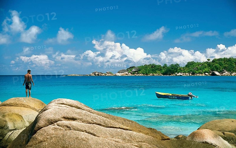 Rocky beach with a local fisherman and a fishing boat