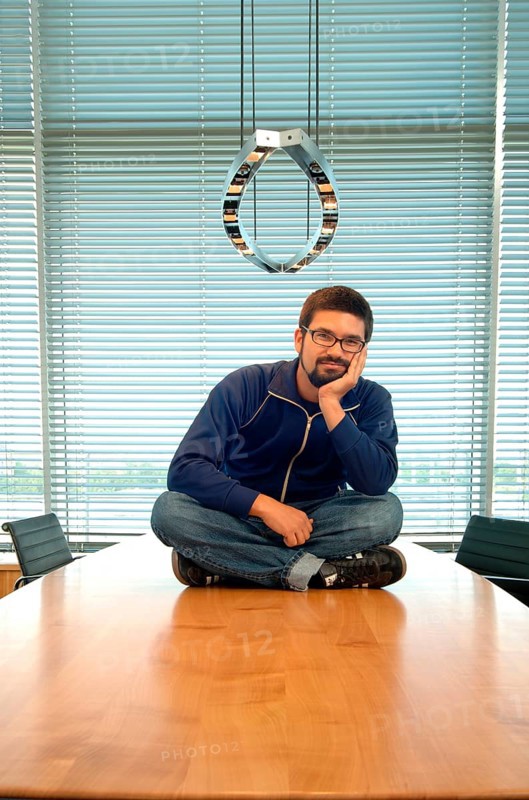 Young man sitting cross-legged on a conference desk