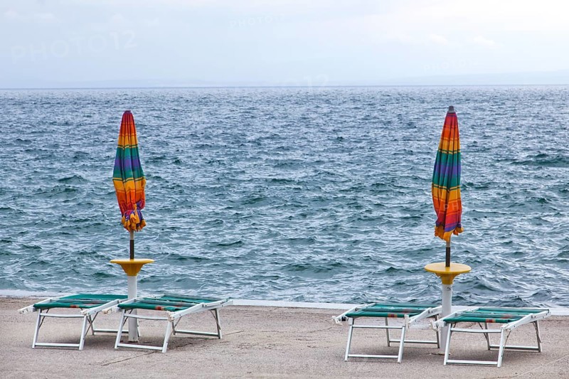 Umbrellas and deckchairs during the preseason on the beach of Opatija on the Mediterranean Sea in Kvarner Bay