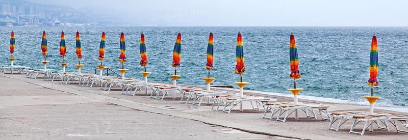 Umbrellas and deckchairs during the preseason on the beach of Opatija on the Mediterranean Sea in Kvarner Bay