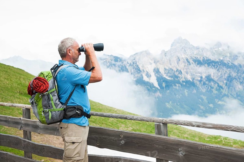 Hiker looking at the Tannheim mountains with binoculars