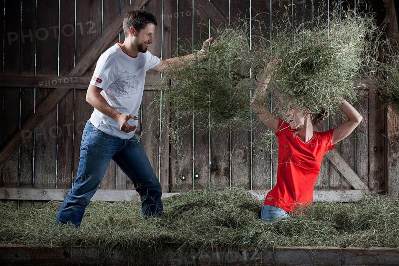 Young couple throwing hay at each other on a farm