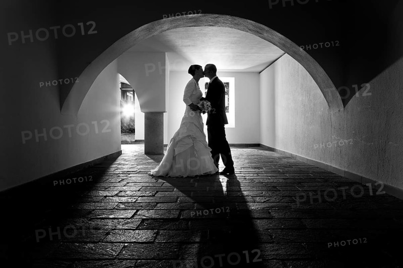 Bride and groom kissing under the arch of an old vault