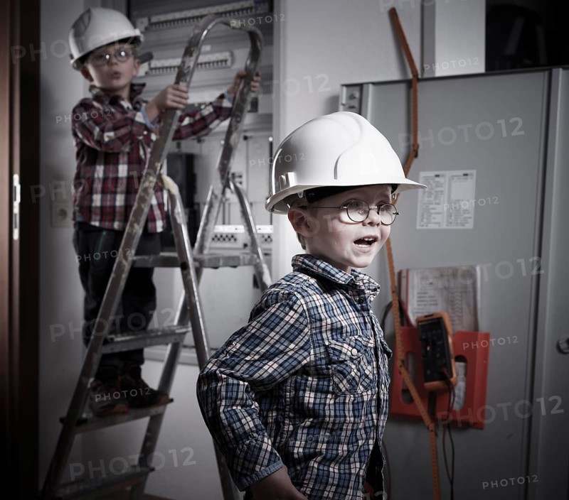 Two boys wearing helmets playing construction workers