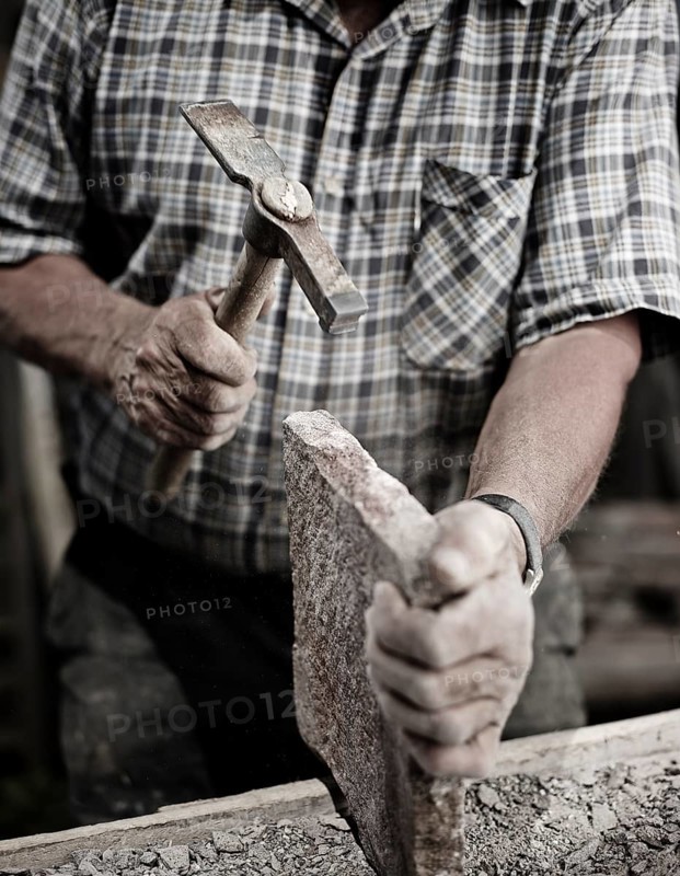 Stonemason working on a stone slab with a hammer