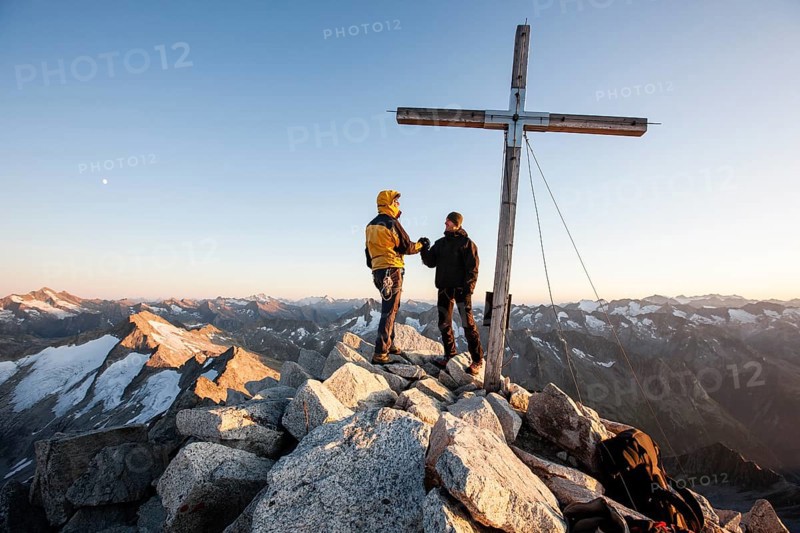 Mountain climbers on the summit cross of Reichenspitze Mountain