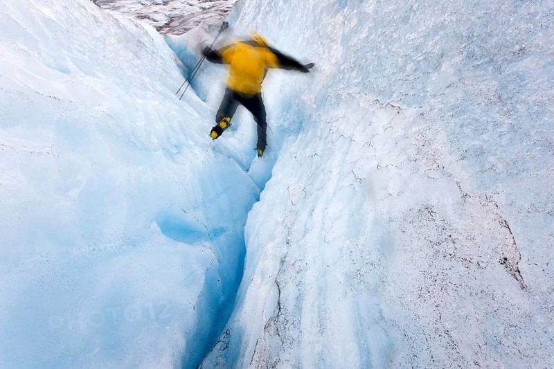Mountaineer jumping into a small crevasse on Matanuska Glacier